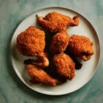 some pieces of Kentucky Fried Chicken thighs on a plate.